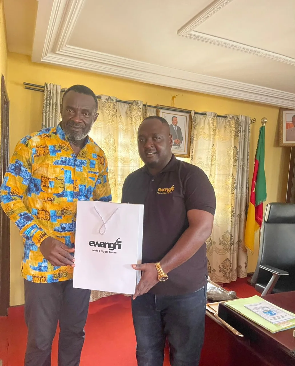 The CEO of Ewanghi Construction company, Abwa Tarkang presenting a packed containing products and services of the company to the Kumba city mayor Gregory N.Mewanu